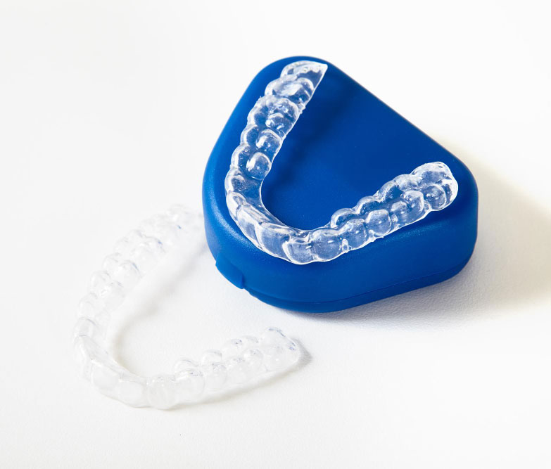 Clear dental aligners resting on a blue case, ready for wear or storage.