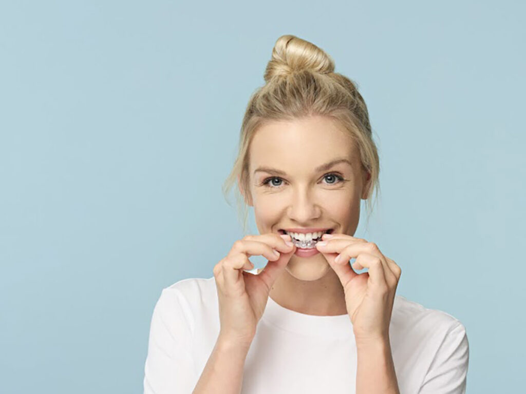 Woman inserting clear aligners in Claremont CA, showing Invisalign treatment for straight teeth at Inland Empire orthodontist