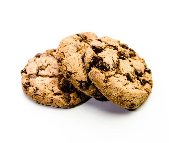 Three chocolate chip cookies stacked together on a light gray background.